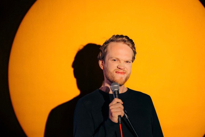 a man wearing black clothes holding a microphone