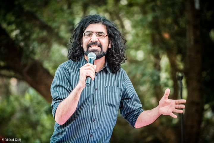 a man standing in front of a tree holding a microphone