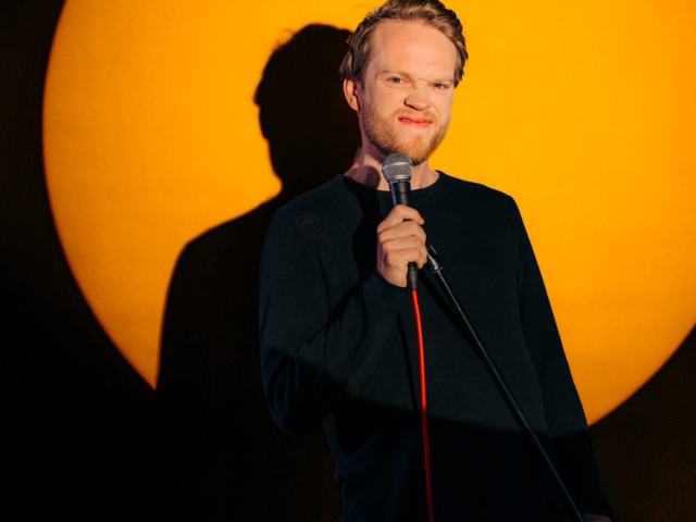 shoot uicf a man wearing a suit and tie and holding a microphone