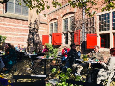 a group of people sitting in a garden at cute coffee places Amsterdam